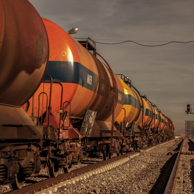 Freight train hauling tank cars along a railway track at dusk
