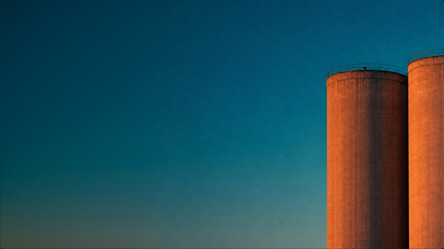 Two rust-orange silos against a teal sky