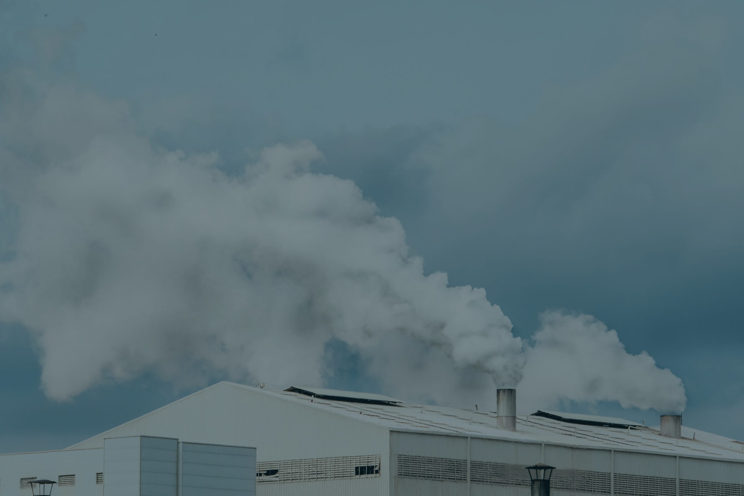 Steam plumes rising from the roof of an industrial hall