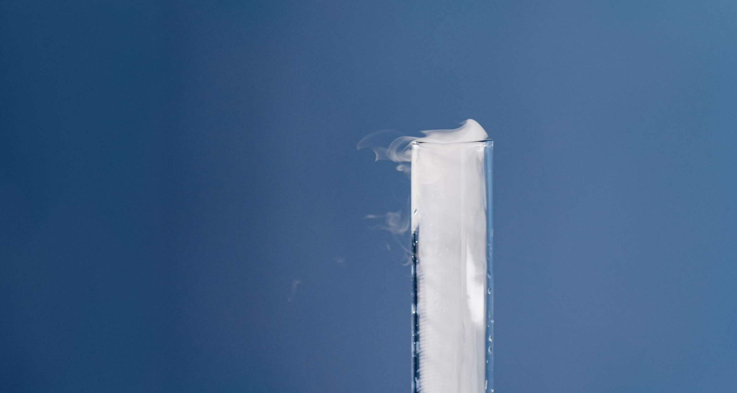 Test tube releasing vapor against a blue sky